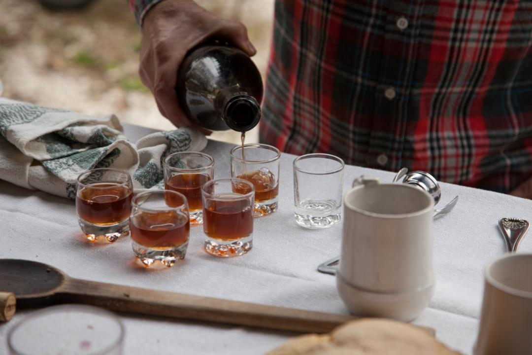 A close-up shot of a person pouring liquid from a bottle into tasting glasses as part of a festival or event
