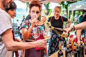 A close-up of wine lovers at the Radda Nel Bicchiere event, tasting white wine as a person pours from a bottle